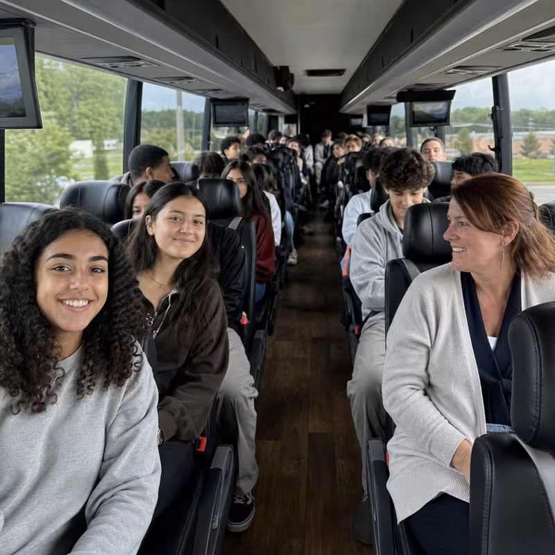 Group boarding a white charter bus for School Transportation transportation in San Diego
